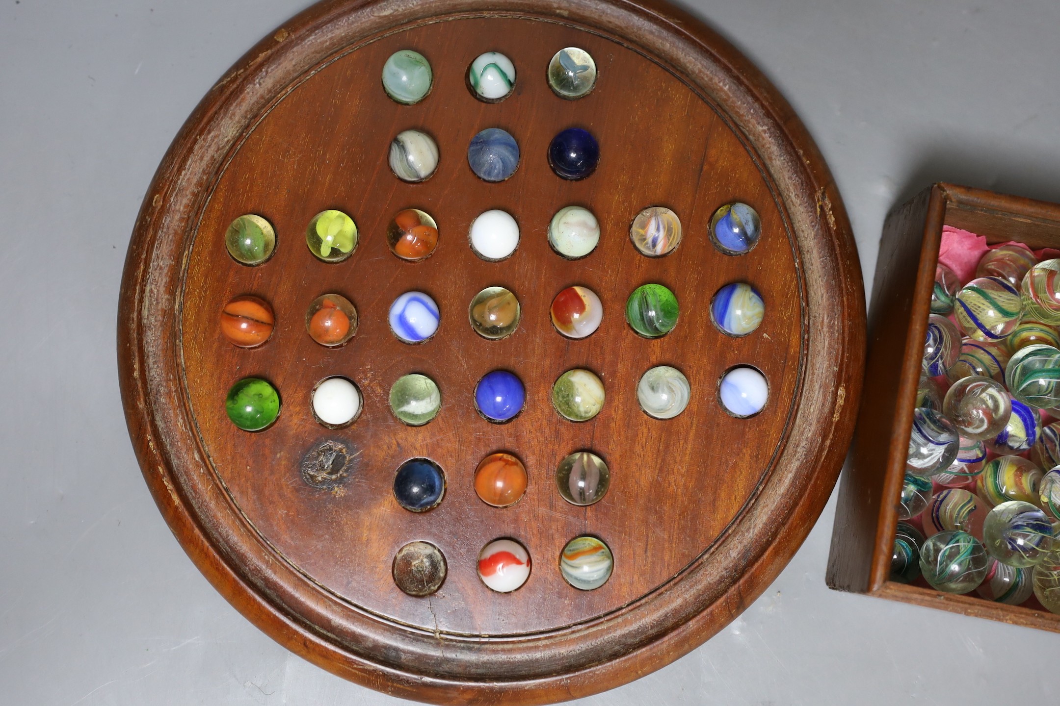 A mahogany solitaire board and marbles